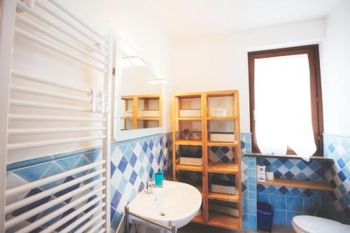 uma casa de banho com paredes em azulejos azuis e brancos e um lavatório. em Il Terrazzo di Lucrezia - Goelba em Nisporto