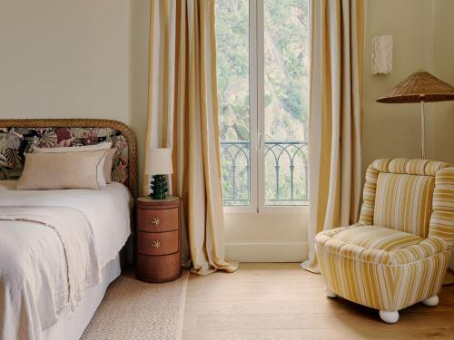 a bedroom with a bed and a chair and a window at Hôtel La Pérouse Nice Baie des Anges - Recently fully renovated in Nice