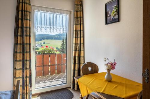 a dining room with a yellow table and a window at Waldesruh in Titisee-Neustadt