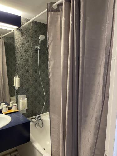 a bathroom with a shower curtain and a sink at Cit'Hôtel le Welcome in Moutiers