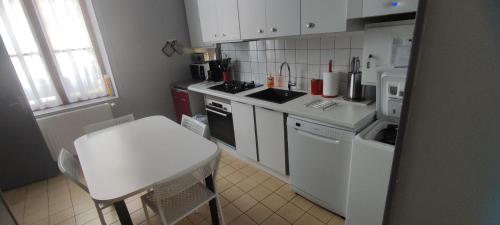 uma cozinha com electrodomésticos brancos e uma mesa e cadeira brancas em Gite de l'ecole 