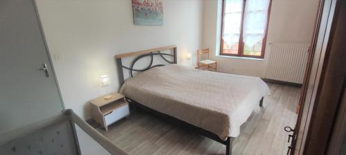 um pequeno quarto com uma cama e uma janela em Gite de l'ecole 
