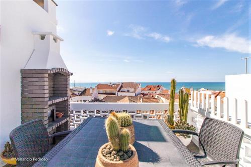 a balcony with chairs and cacti and the ocean at Nesha Ericeira Flats in Ericeira