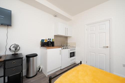 cocina con armarios blancos y puerta blanca en Brinton's Road - Modern Studio Apartments in City Centre en Southampton
