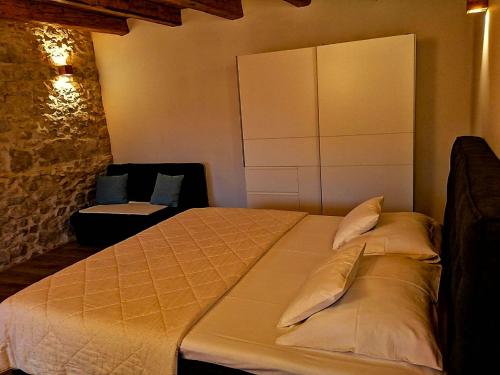 1 dormitorio con 1 cama grande y 1 silla en Apartments Dalmatian Stone House, en Turanj
