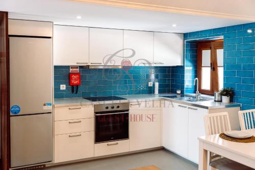 a kitchen with white cabinets and blue tiles at Cancela Velha Guest•House in Marco de Canaveses