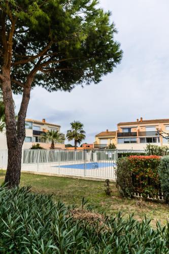 une clôture blanche et un arbre dans une cour dans l'établissement Cap d'Agde Suit'Appart T1 Pinède 26 m2 balcon 10 m2, au Cap d'Agde
