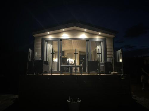 una casa con un portico schermato di notte di Lake District Luxury Lodge a Plumbland