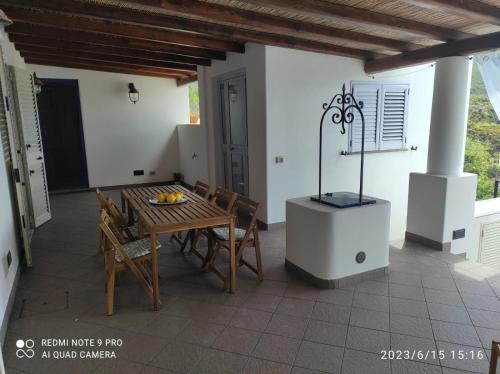 a patio with a table and chairs and a stove at Appartamento Rocche Rosse in Acquacalda