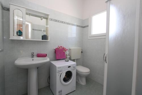een badkamer met een wastafel en een wasmachine bij Ville Pinetine in Bibione