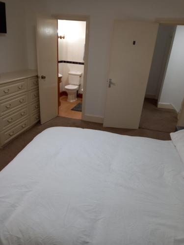 a bedroom with a large white bed and a bathroom at The Great Beecholme in Streatham Vale