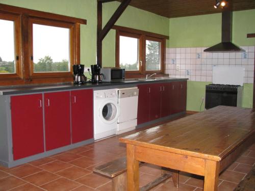 a kitchen with a washing machine and a wooden table at L'escaille in Brognon