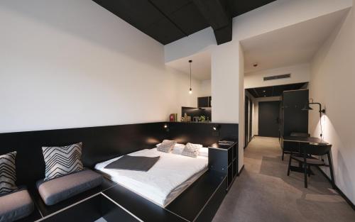 a bedroom with a black bed and a desk at MoLiving - Design Hotel & Apartments Düsseldorf-Neuss in Neuss