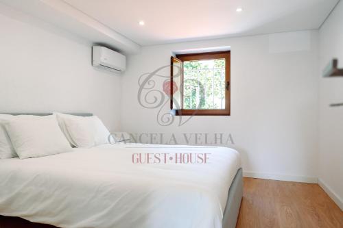 1 dormitorio con cama blanca y ventana en Cancela Velha Guest•House en Marco de Canavezes