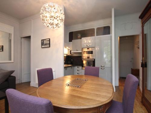 une cuisine et une salle à manger avec une table en bois et des chaises violettes dans l'établissement T1 splendide avec balcon et WIFI - 4 personnes - FR-1-608-46, à Le Mont-Dore