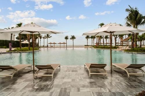 uma piscina num resort com cadeiras e guarda-sóis em Dhawa Ho Tram em Ho Tram