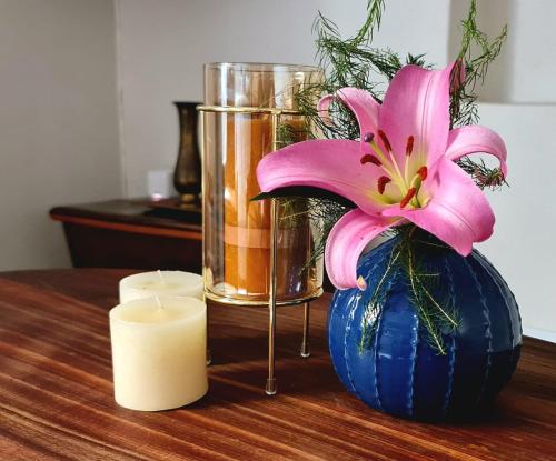 una flor rosa en un jarrón azul junto a una vela en Luxury Cottage - Malmesbury, en Malmesbury