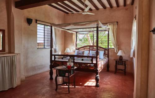 ein Schlafzimmer mit einem Himmelbett und einem Fenster in der Unterkunft Banana House and Wellness Centre in Lamu