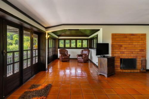 a living room with a tv and chairs and windows at Isatour - Ninho D' Águia in Águeda