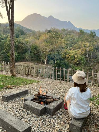a woman sitting in front of a fire pit at Sky The Campers in Chiang Dao
