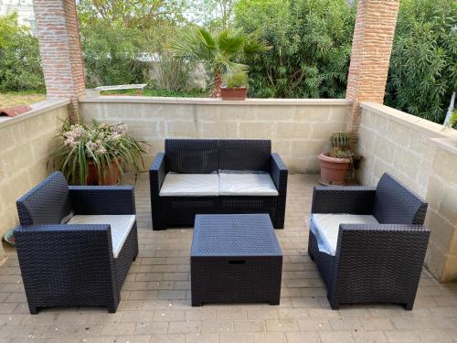 a patio with four chairs and a couch and tables at Il Casolare Degli Ulivi in Oria