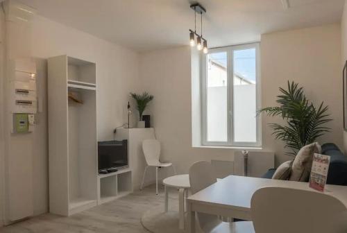 a white living room with a table and a tv at Charme de Loire à St Ay *T2* in Saint-Ay