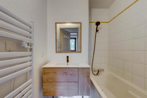 y baño con lavabo, espejo y bañera. en Le Goléron des Evettes en Flumet