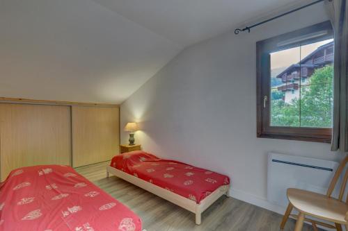 a bedroom with a red bed and a window at Le Goléron des Evettes in Flumet