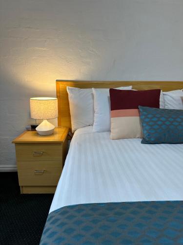 a bedroom with a bed with pillows and a night stand at Grand Country Lodge Motel in Mittagong