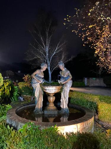 a statue of two men sitting in a fountain at night at Grand Country Lodge Motel in Mittagong