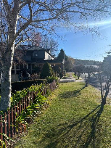 a yard with a fence and trees and a house at Grand Country Lodge Motel in Mittagong