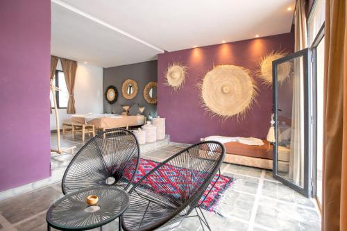 a room with two chairs and a bedroom with purple walls at La Fattoria Ecolodge in Lalla Takerkoust