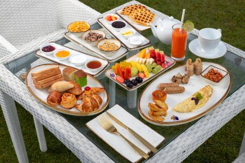 a table with plates of breakfast food on it at The Westbury Palace in Nuwara Eliya