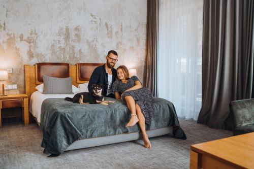 a man and a woman sitting on a bed with a dog at Gabija Hotel SPA & Conferences in Palanga