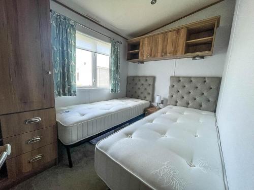 a small bedroom with two beds and a window at Beautiful Caravan With Decking At Carlton Meres Holiday Park, Suffolk Ref 60022m in Saxmundham