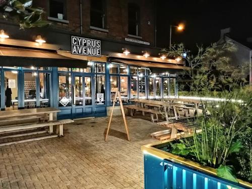 a restaurant with benches in front of it at night at Stylish 2BR Cottage Garden & Parking 5 mins to Titanic in Belfast