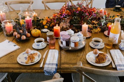 a wooden table topped with plates of food and candles at La Maison d’Hôtes in Silly