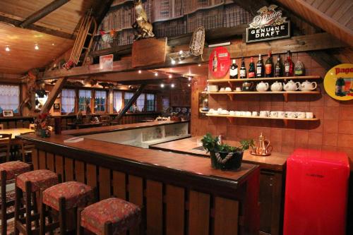a restaurant with a bar with stools and bottles of beer at Guest House Chalet Saint Roch in Albiez-Montrond