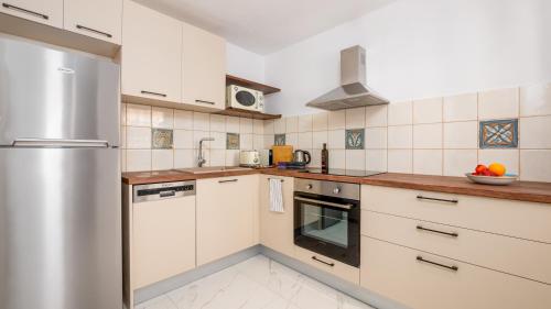 a kitchen with white cabinets and a stainless steel refrigerator at Pamina Mare in Nea Skioni