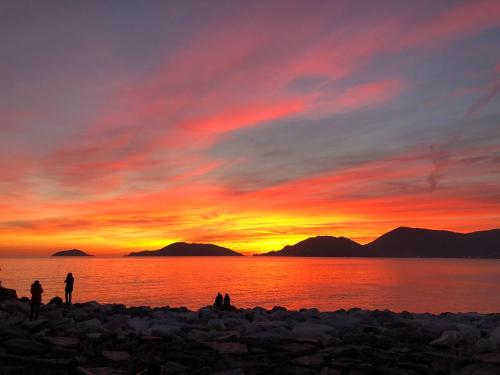 a group of people standing on a beach at sunset at Il frantoio di Olimpia in Lerici