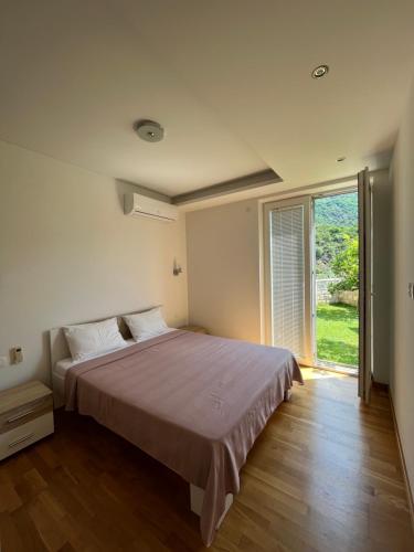 a bedroom with a large bed and a large window at Family Lux Apartments - Lemon Garden and Pool in Becici