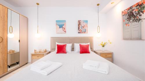 a bedroom with a large white bed with red pillows at Pamina Mare in Nea Skioni