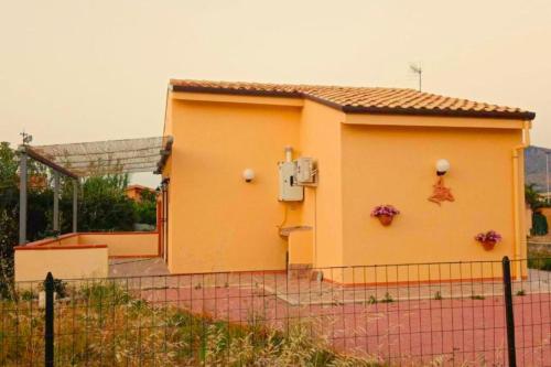 a yellow house with a fence in front of it at Villa House of William in Lascari
