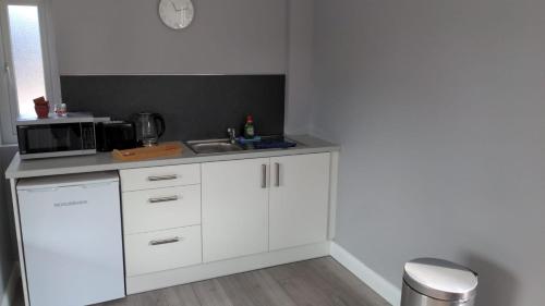 a white kitchen with a sink and a microwave at Valley Stream Guest Accommodation in Moira