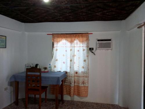 een kamer met een tafel en een raam met een tafel en een stoel bij Nine Clouds Homestyle Accommodation in General Luna