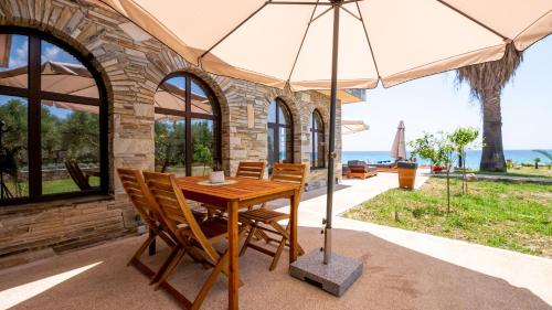 a wooden table with chairs and an umbrella at Pamina Mare in Nea Skioni