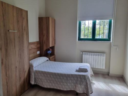 a small bedroom with a bed and a window at Casa Diocesana VIA LUCIS in Santiago de Compostela