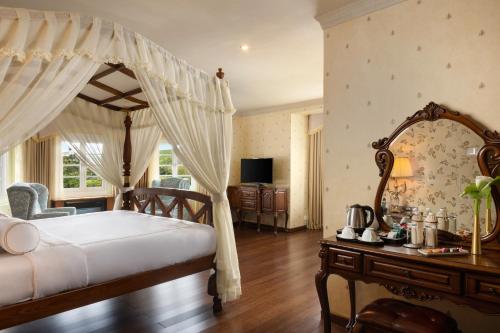 a bedroom with a canopy bed with a table and a mirror at The Westbury Palace in Nuwara Eliya