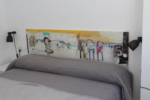 a bedroom with a bed with a painting above it at ÁTICO CENTRO in Yecla