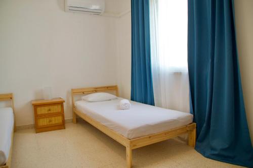 een kleine slaapkamer met een bed en blauwe gordijnen bij Yiallos Village Apt. A101 in Menevi